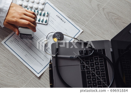 Male doctor in public medical office is stamping medical document. Healthcare concept. Top view Male doctor in public medical office is stamping medical document. Healthcare concept. Top view 69691884