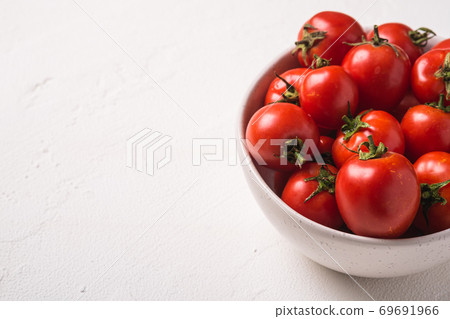 Fresh ripe tomatoes with water drops in bowl on white concrete background, angle view copy space Fresh ripe tomatoes with water drops in bowl on white concrete background, angle view copy space 69691966