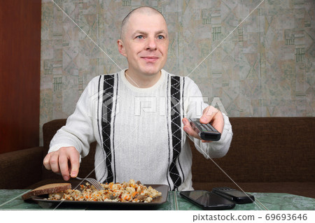 the man eats rice pilaf and stares of TV program the man eats rice pilaf and stares of TV program 69693646