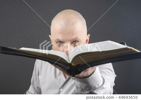 man looks through an open Bible man looks through an open Bible 69693650