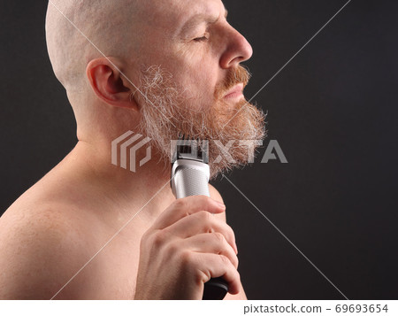 Bearded man with trimmer to adjust beard in hand Bearded man with trimmer to adjust beard in hand 69693654