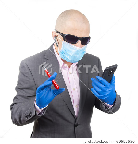 Successful businessman in a protective mask and gloves works on a smartphone during quarantine Successful businessman in a protective mask and gloves works on a smartphone during quarantine 69693656