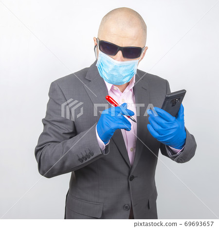 businessman in a mask and gloves works on a smartphone during quarantine of the coronavirus businessman in a mask and gloves works on a smartphone during quarantine of the coronavirus 69693657