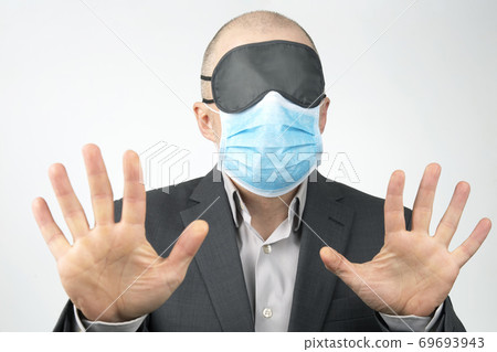 business man in a medical mask and blindfold for sleeping with hands up on a white background business man in a medical mask and blindfold for sleeping with hands up on a white background 69693943