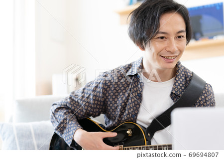 A man playing a band online [Living] 69694807