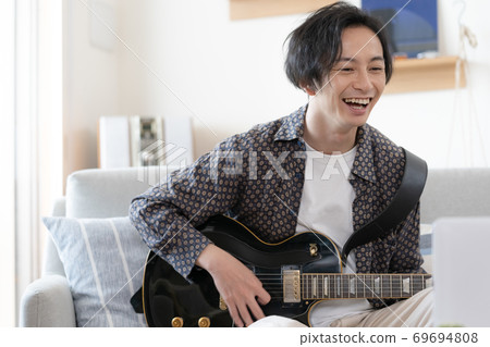 A man playing a band online [Living] 69694808