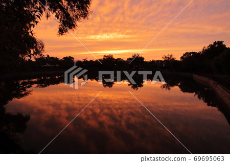 反射天空的水面被夕陽染成紅色 反射天空的水面被夕陽染成紅色 69695063