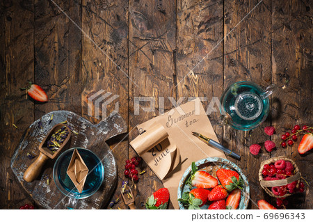 Berry still life. Berries, tea, pen, calendar, notebook on an old brown wooden table, top view Berry still life. Berries, tea, pen, calendar, notebook on an old brown wooden table, top view 69696343