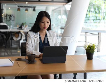 Businesswoman typing on tablet keyboard while working in office room 69696969