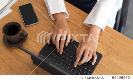 Businesswoman typing on tablet keyboard on wooden table 69696970