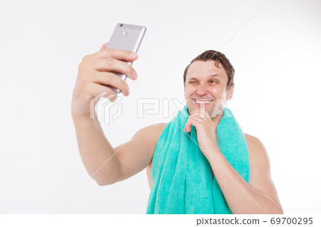 the guy takes a selfie after morning procedures. A man looks at the phone camera. Smooth-shaven face. Blue towel around her neck. Man and modern technologies. the conversation via video link the guy takes a selfie after morning procedures. A man looks at the phone camera. Smooth-shaven face. Blue towel around her neck. Man and modern technologies. the conversation via video link 69700295