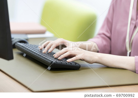 A woman's hand hitting the keyboard of a desktop computer 69700992
