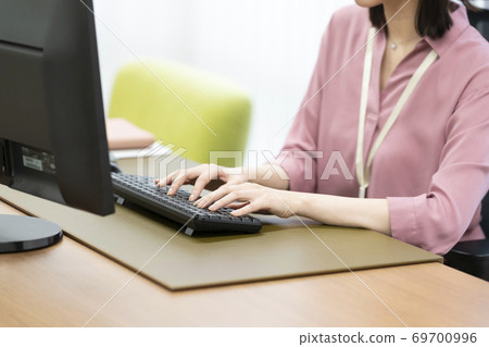 A woman's hand hitting the keyboard of a desktop computer 69700996
