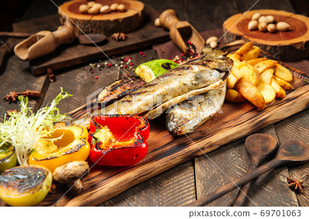 Grilled fish with vegetables on the wooden board 69701063