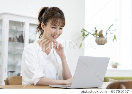 一個女人看著一台便攜式計算機的屏幕 一個女人看著一台便攜式計算機的屏幕 69701067