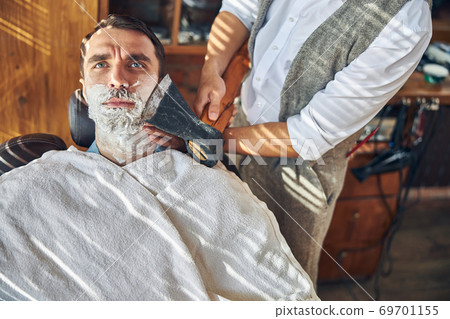 Concerned client of a barbershop being shaved with an axe Concerned client of a barbershop being shaved with an axe 69701155