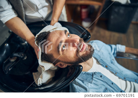 Bearded brunette man getting a barbershop staff dry his hair Bearded brunette man getting a barbershop staff dry his hair 69701191