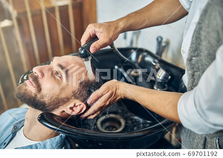 Chilled young customer of a barbershop having a hair wash Chilled young customer of a barbershop having a hair wash 69701192