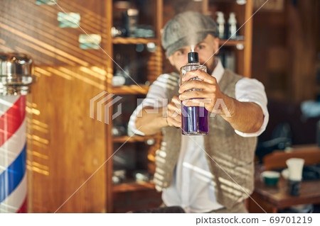 Stylish hairdresser spraying moisture mist into the air Stylish hairdresser spraying moisture mist into the air 69701219