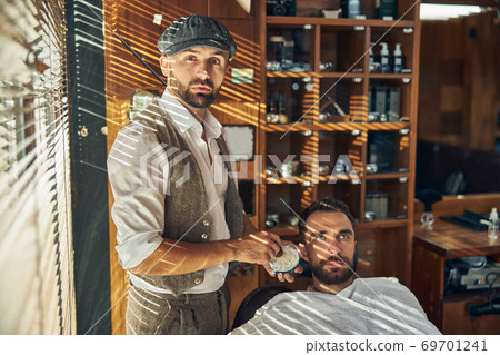 Fancy barber getting ready to shave his client beard Fancy barber getting ready to shave his client beard 69701241
