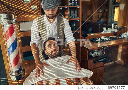 Responsible hair-grooming specialist providing his visitor with a towel Responsible hair-grooming specialist providing his visitor with a towel 69701277