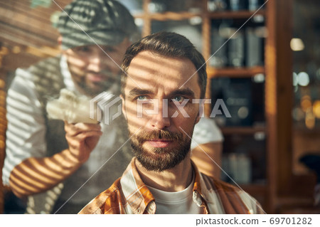 Grey-eyed hipster with a beard waiting to get a haircut Grey-eyed hipster with a beard waiting to get a haircut 69701282