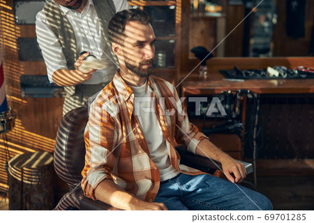 Brunette young man getting a fresh shave a barbershop Brunette young man getting a fresh shave a barbershop 69701285