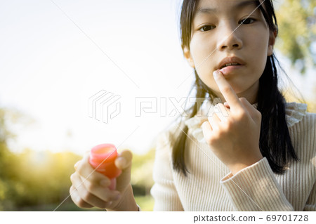 Asian child girl maintains her lips,skin care and protection, chapped lips,dry mouth that have lost moisture,beautiful female teenage applied balm to repair her lips in winter cold,woman with natural Asian child girl maintains her lips,skin care and protection, chapped lips,dry mouth that have lost moisture,beautiful female teenage applied balm to repair her lips in winter cold,woman with natural 69701728