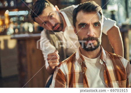 Brunette barbershop visitor having his hair done at barbershop 69701915
