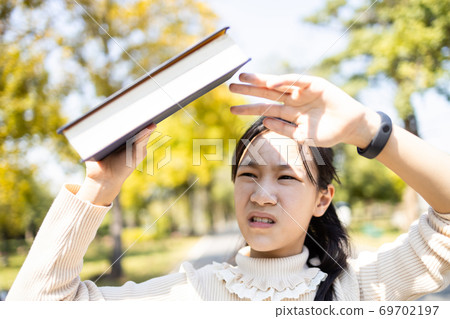 Asian child girl hold a book covering the sun to prevent facial skin damage,sunlight UV rays problem to make melasma and freckles,female people worried about hot strong sunburn attacking the face,skin Asian child girl hold a book covering the sun to prevent facial skin damage,sunlight UV rays problem to make melasma and freckles,female people worried about hot strong sunburn attacking the face,skin 69702197
