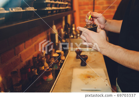 A person takes tobacco. The person is preparing a hookah. There is a table. A person takes tobacco. The person is preparing a hookah. There is a table. 69703337