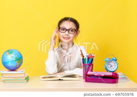 The schoolgirl sits at the desk and raises her hand for an answer. Back to school. The new school year. 69703976