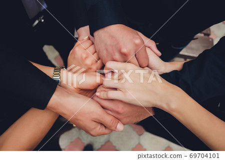 two man and three women holding hands on a table implying a polyamory relationship or love triangle. 69704101