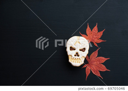 Creepy funny skull shaped Halloween cookies and dry autumn leaves. Creepy funny skull shaped Halloween cookies and dry autumn leaves. 69705046