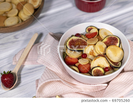 Trendy home breakfast with small pancakes and strawberry, currant and slieces of figs on white table. Top view of treandy breakfast. Trendy home breakfast with small pancakes and strawberry, currant and slieces of figs on white table. Top view of treandy breakfast. 69705260