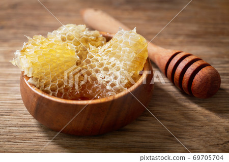 bowl with honeycombs pieces on a wooden table 69705704