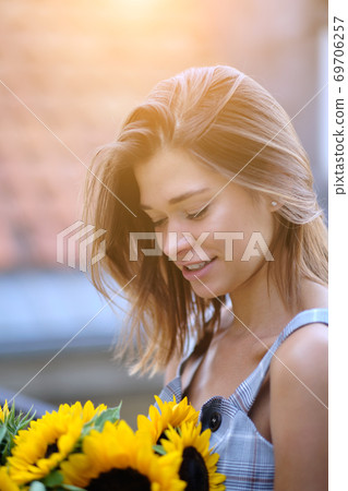 woman is walking in the old town. He is holding a bouquet of autumn sunflowers in his hand woman is walking in the old town. He is holding a bouquet of autumn sunflowers in his hand 69706257