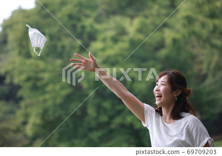 A woman happily throwing a mask A woman happily throwing a mask 69709203