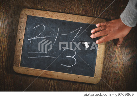 Child hand after writing simple math calculation on small blackboard with chalk Child hand after writing simple math calculation on small blackboard with chalk 69709869