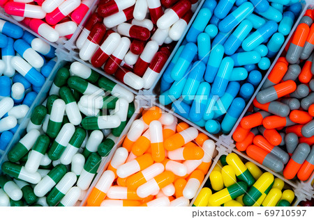 Top view of antibiotic capsule pills in plastic tray. Antibiotic drug resistance. Pharmacy products. Healthcare and medicine. Full frame of red, blue, green, yellow, orange, and gray capsule pills. 69710597