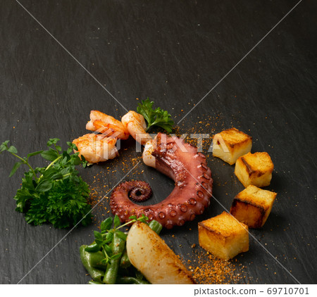 Grilled octopus tentacle on black stone plate served with shrimps 69710701