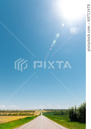 Empty country road on a summer day with green plantings of forest and greenery on the sides 69711478