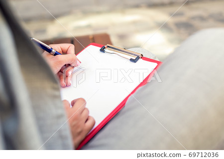 Female hand writing on a blank planner Female hand writing on a blank planner 69712036