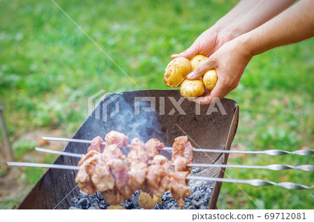 Man prepares barbecue meat with potatoes Man prepares barbecue meat with potatoes 69712081