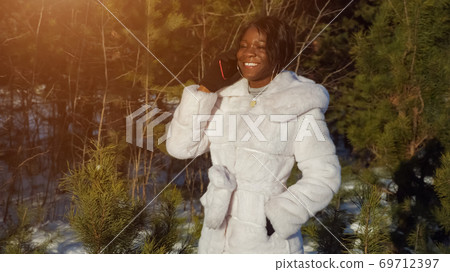 black woman talks on phone with friends against green plants black woman talks on phone with friends against green plants 69712397