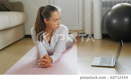 young lady does sports exercises watching video on floor young lady does sports exercises watching video on floor 69712434
