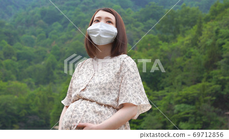 Pregnant woman in a mask in the woods Pregnant woman in a mask in the woods 69712856