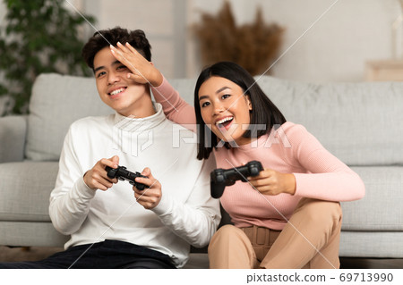 Happy Asian Couple Playing Computer Video Game Sitting At Home 69713990