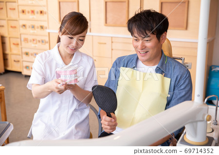 Dental hygienist and male patient 69714352