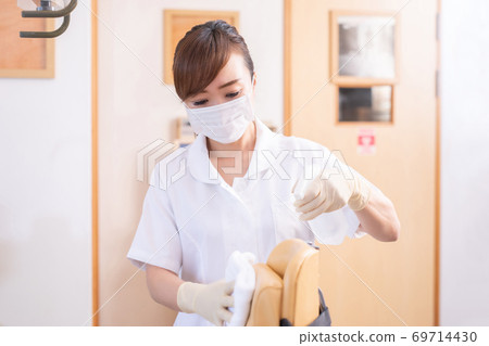 A woman in a white coat disinfecting a hospital room 69714430